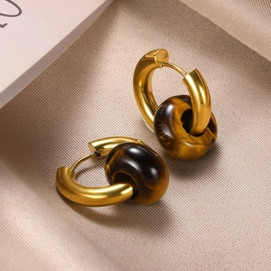 Macro shot of gold hoop earrings featuring polished tiger eye stone doughnut charms