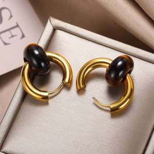 Macro detail of vintage gold hoop earrings with brown gemstone beads on silk fabric