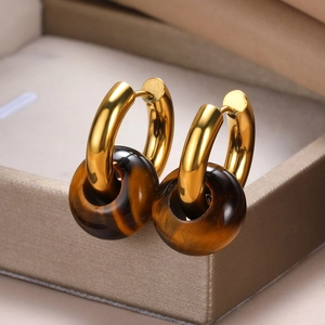 Macro shot of gold hoop earrings with tiger eye stone rings on a jewelry box edge