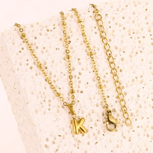 Detailed view of gold letter K pendant on a beaded chain with lobster clasp and extender