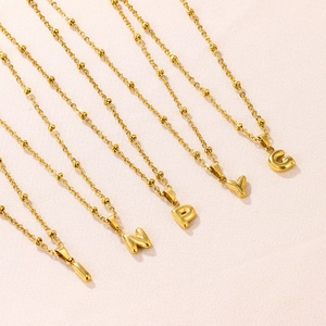 Close-up of 18K gold plated bubble letter pendants on a satellite bead chain necklace