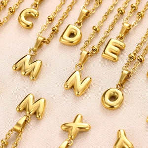 Macro shot of gold bubble alphabet pendants featuring polished 18K gold plated steel texture