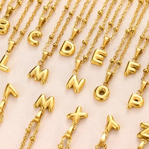 Detailed macro view of 18K gold plated bubble letter pendants on bead chains