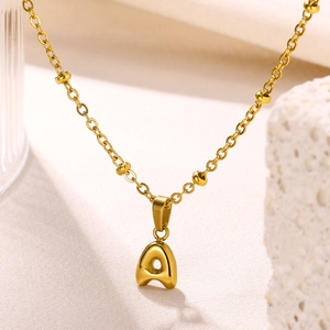 Detail shot of a 18K gold-plated bubble letter A pendant on a delicate beaded chain