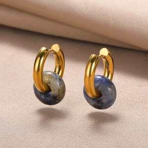 Macro view of gold hoop earrings featuring polished blue natural stone donut charms