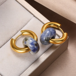 Macro view of gold hoop earrings with blue natural marble stone on gray jewelry box