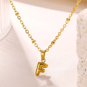 Detailed macro view of an 18K gold plated bubble letter F pendant on a beaded chain