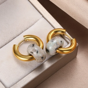 Close-up of vintage golden donut earrings with natural stone beads on silk fabric