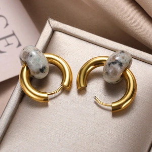 Macro shot of gold hoop earrings with marble stone beads in a luxury jewelry box