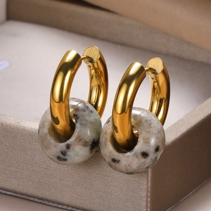Macro detail of donut-shaped natural spotted stone earrings with gold metal hoops