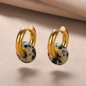 Macro detail of gold hoop earrings with natural Dalmatian Jasper stone donut charms