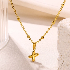 Detail of 18K gold-plated bubble cross pendant on beaded necklace with elegant indoor lighting