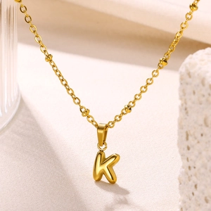 Macro shot of 18K gold plated stainless steel bubble letter K pendant on a beaded chain