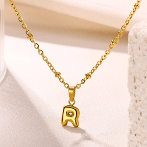 Detailed macro view of 18K gold plated bubble letter R pendant on a beaded cross chain
