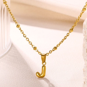 Macro detail of 18K gold plated bubble letter J pendant necklace with small beads