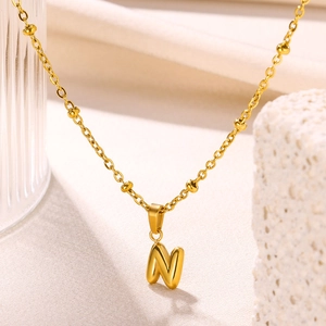 Detail of 18K gold-plated necklace with beaded chain and bubble letter N pendant