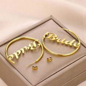 Detail der großen goldenen Creolen mit kursivem Bride-Schriftzug für Hochzeiten