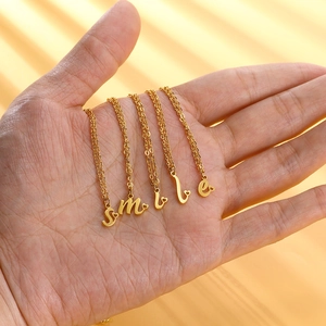 Dettaglio di collane in acciaio dorato con lettere smile e piccoli ciondoli a cuore
