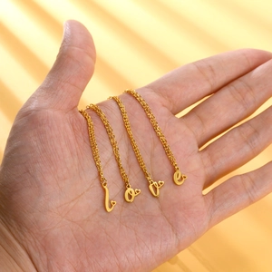 Dettaglio di quattro catene in oro con ciondoli a lettere love e piccoli cuoricini
