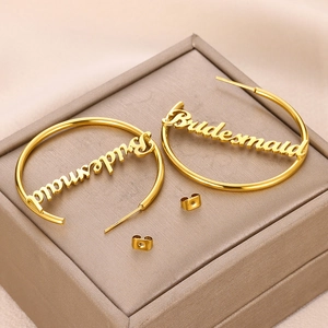 Details der goldenen Creolen mit Bridesmaid-Schriftzug auf einer Champagner-Schmuckschatulle