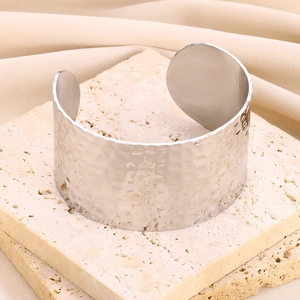 Close-up of a silver wide hammered metal cuff bracelet on natural stone background
