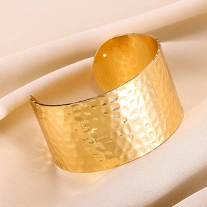 Detailed view of wide gold cuff bracelet featuring a unique hammered texture finish