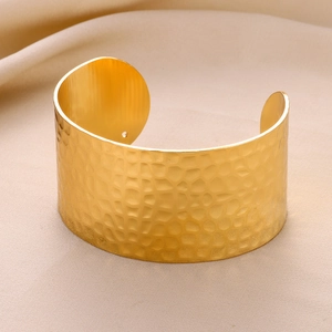 Close-up of golden wide open cuff bracelet featuring an elegant hammered metal texture