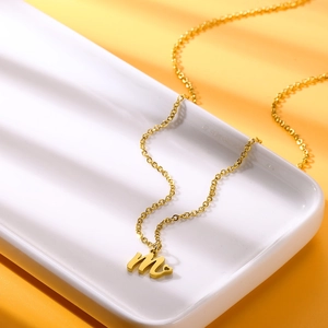 Dettaglio ravvicinato di una collana dorata con pendente a lettera M su vassoio bianco
