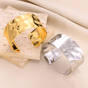 Hammered titanium steel wide open bangles in gold and silver on a stone display
