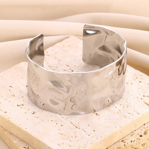 Detailed view of wide silver steel cuff with hammered texture on stone base