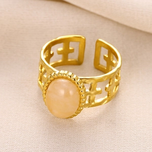 Macro view of gold stainless steel ring with hollow cross pattern and orange stone