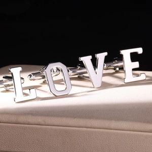 Polished silver stainless steel letter cufflinks spelling LOVE on a leather stand