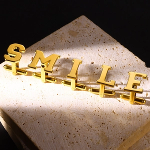 Macro shot of gold alphabet SMILE cufflinks on textured stone with a dark background