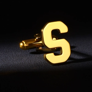 Detailed macro view of a gold letter S cufflink with a high-polished mirror finish