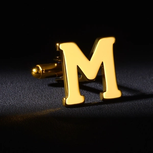 Macro shot of gold stainless steel letter M cufflink for men with classic swivel back