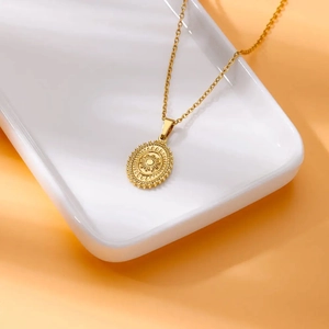 18K gold plated stainless steel necklace featuring an oval sunburst pendant on a white plate