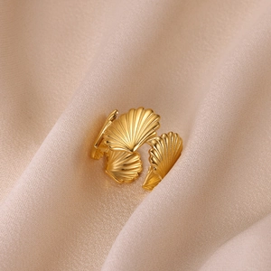 Primo piano di un anello a conchiglia dorato con trama radiale su seta beige elegante