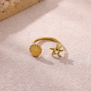 Dettaglio dell'anello marino dorato regolabile con conchiglia, stella marina e zircone