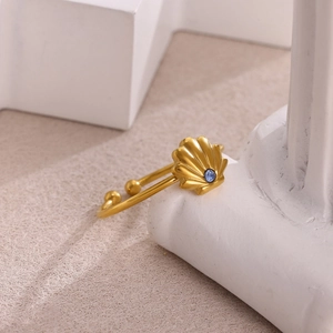 Dettaglio macro di un anello a conchiglia dorato con cristallo blu su supporto