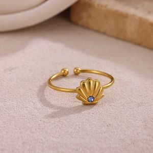 Dettaglio dell'anello dorato regolabile con motivo a conchiglia e zircone blu su pietra