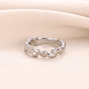 Détail d'une bague vague argentée irrégulière sur fond de soie douce au fini poli