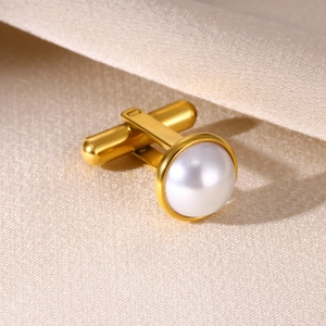 Men's gold-plated cufflink with a large white pearl inlay on a champagne satin background