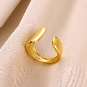 Gros plan détaillé d'une bague ouverte cœur en or mat sur fond de soie beige clair