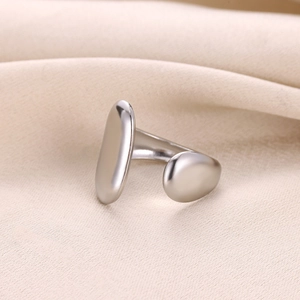 Détail d'une bague ajustable argentée au design géométrique sur du tissu en soie