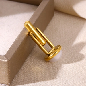 Gros plan d'un bouton de manchette doré élégant avec perle blanche sur tissu en soie