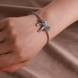 Gros plan d'un bracelet nœud en acier inoxydable argenté porté au poignet poli et lisse