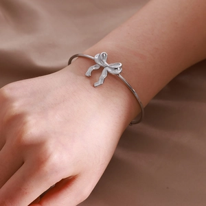 Vue détaillée d'un bracelet jonc argenté avec nœud papillon porté au poignet avec élégance