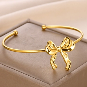 Bracelet jonc ouvert en acier inoxydable doré avec nœud papillon et fini poli miroir