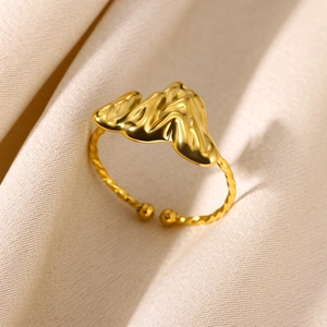 Detailed view of adjustable golden twist ring with irregular wave folds and mirror finish