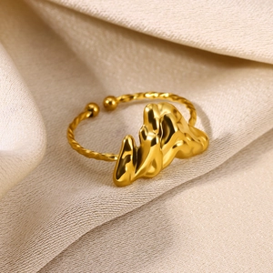 Macro view of adjustable gold ring with wavy geometry on soft beige silk fabric